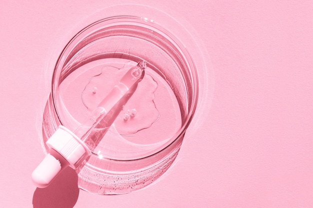 Petrischaal Met transparante gel De pipet ligt Cosmetische dispenser Op een roze achtergrond