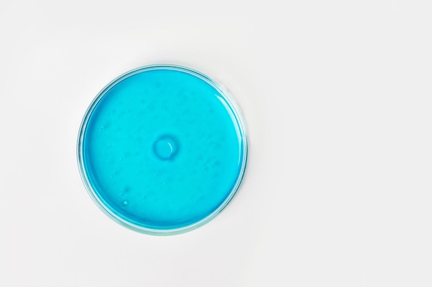 Petrischaal op een lichte achtergrond Met blauwe of blauwe vloeistof Watervlekken oliedruppels Grote bacterie of virus in het midden Ei Laboratoriumglaswerk studie Chemische elementen