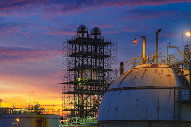 Foto impianto petrolchimico sullo sfondo del cielo al tramonto con serbatoio a sfera di stoccaggio del gas