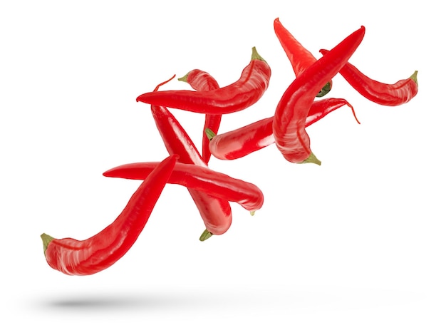 Peulen van rode hete pepers van verschillende maten en vormen vallen op een witte geïsoleerde achtergrond die een schaduw werpt Verse rode peper voor invoeging in ontwerp of project geïsoleerd op wit close-up