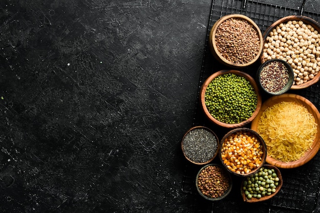 Peulvruchten een set bestaande uit verschillende soorten bonen, linzen en erwten, rijst en boekweit op een zwarte achtergrond bovenaanzicht Het concept van gezond en voedzaam voedsel