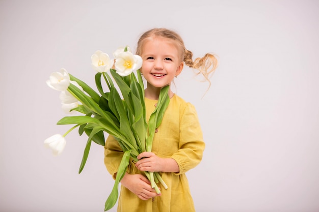 peuter blond meisje in groene jurk met tulpen op witte achtergrond