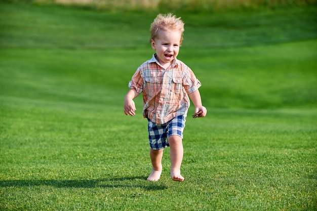 Peuter die zich bij de groene golfbaan op zonnige dag