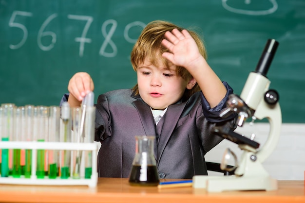 Peuter genie baby jongen in de buurt van Microscoop en reageerbuizen in school klas Technologie en wetenschap concept Kid studie biologie en scheikunde op school School onderwijs Ontdek biologische moleculen