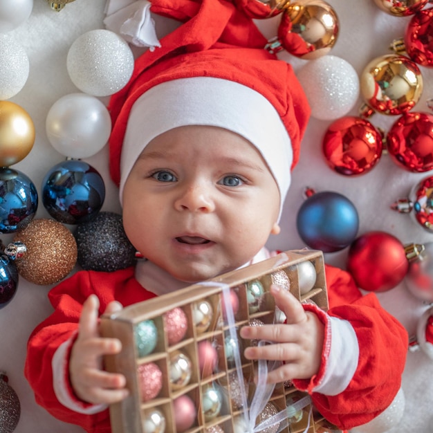 Foto peuter in een pak van de kerstman met kerstboomversieringen.