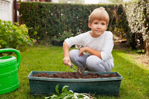 Peuter jongen bodem graven voor groene planten