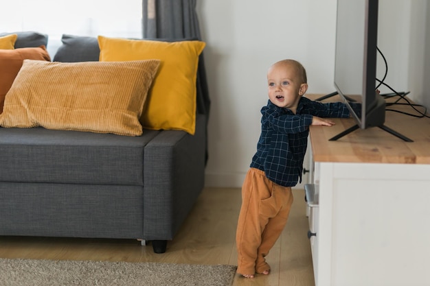 Peuter jongen lachen plezier staande in de buurt van de bank in de woonkamer thuis kopiëren ruimte Schattige baby eerste stappen alleen maken Gelukkige jeugd en kinderopvang concept