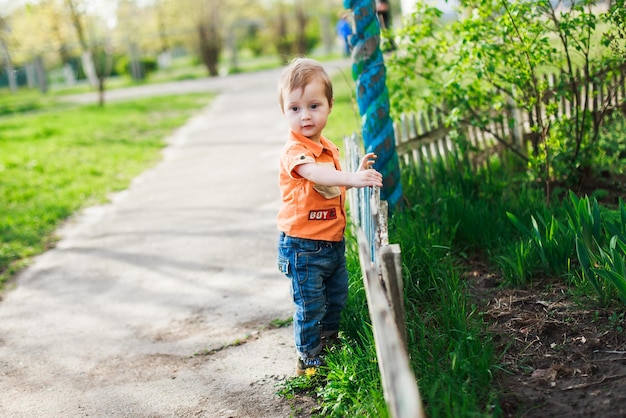 Peuter mooie jongen staande bij het blauwe hek De jongen bleef