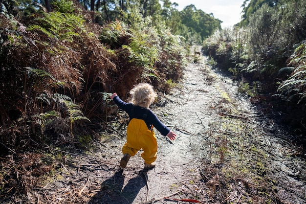 peuter op verkenning in gele overalls in het bos in de winter