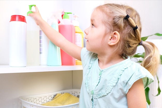 Peuter raakt flessen huishoudelijke chemicaliën, huishoudelijke schoonmaakmiddelen aan. Gevaarlijke situatie