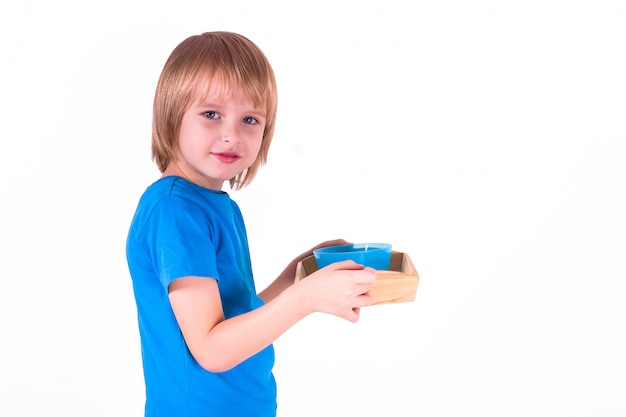 Peuterjongen die zich met een dienblad van Montessori-materialen voor een les van het praktische leven op een witte achtergrond bevindt,