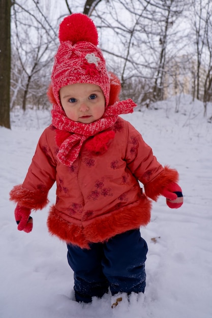 Peutermeisje dat door sneeuw in het park loopt. Frost winterseizoen.