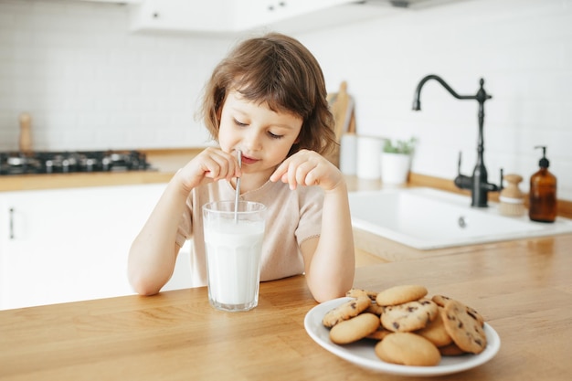 Peutermeisje drinkt melk met stalen rietje van glas Duurzaam leven met kinderen