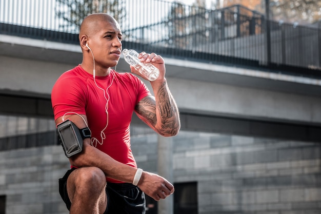 Ph level. Nice tired man drinking fresh cold water while being thirsty after the workout