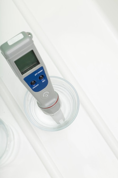 pH meter in a glass of water and bottle on a white background Measurement of the characteristics