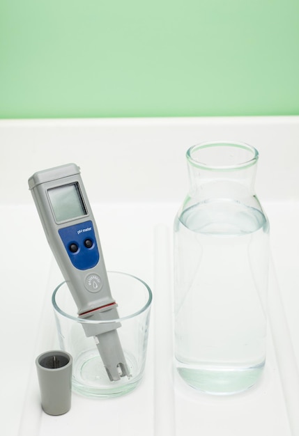 Фото ph-метр в стакане воды и бутылке на белом фоне измерение характеристик
