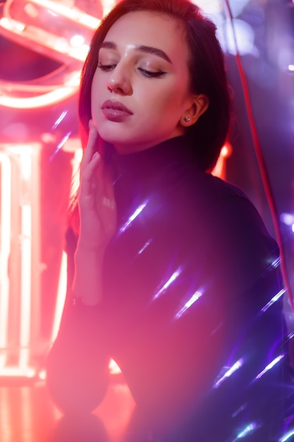 Фото phantom blue 2020 trend.портрет девушки на фоне неоновой вывески витрины. стиль ретроволны с неоновым и розовым огнями.
