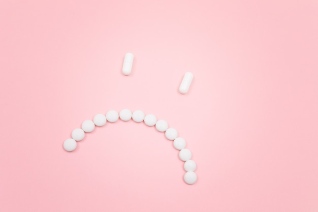 Pharma schaadt droevig smileygezicht gemaakt van witte pillen