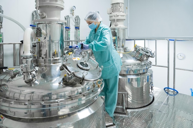 Photo pharmaceutical factory woman worker in protective clothing operating production line in sterile environment