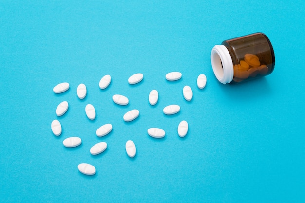 Белые таблетки фармацевтической промышленности и лекарственных препаратов на синем столе