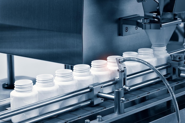 Pharmaceutical industry, medicine pills are filling in the  bottle on production line machine conveyor at the medical factory. selective focus.