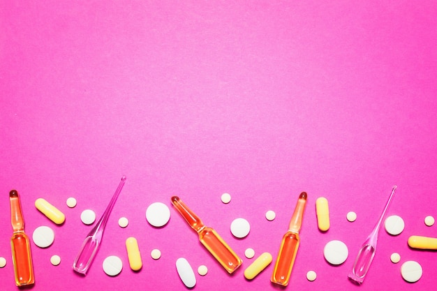 製薬医療ピンクの背景。ピル、アンプル、ピルの上面図。テキストの場所