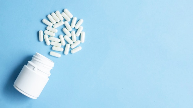 Pharmaceutical medicine pills and capsules with the bottle on blue background and copy space for text.