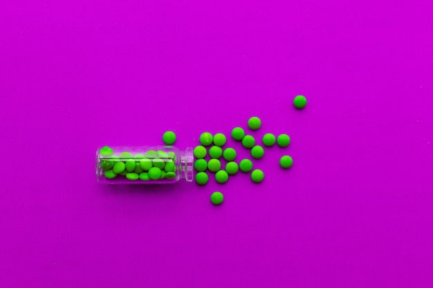 Pharmaceutical medicine tablet green pills on pink background