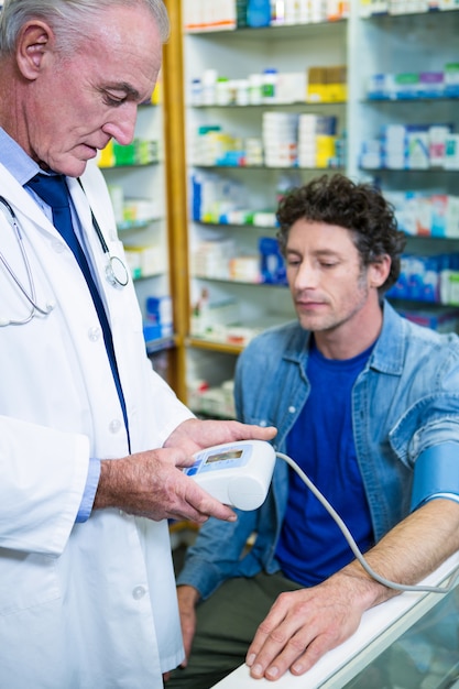 Pharmacist checking blood pressure of customer