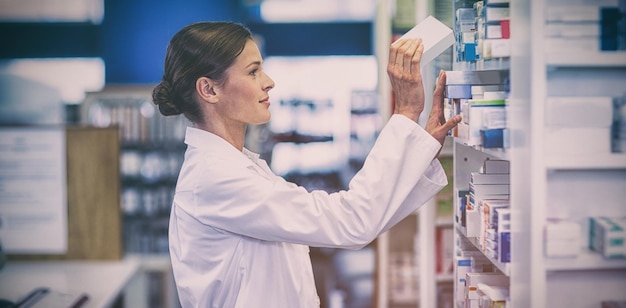 Foto farmacista che controlla la medicina nello scaffale