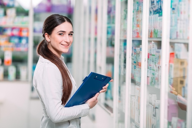 Pharmacist chemist woman working in pharmacy drugstore with tablet.