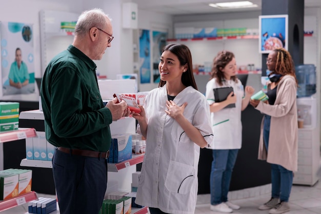 Pharmacist explaining cardiology pills prescription to elderly client during medical consultation in drugstore. Old customer buying pharmaceutical drugs treatment to cure disease. Medicine support