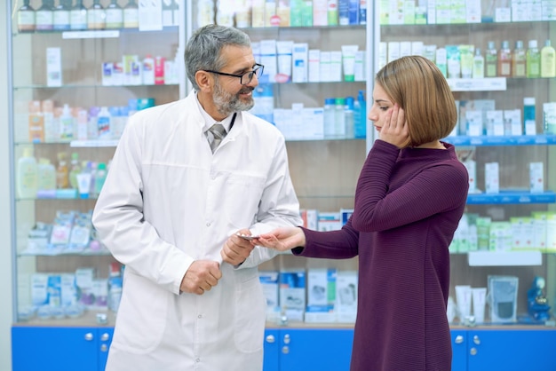 Pharmacist gicing woman with headache pills