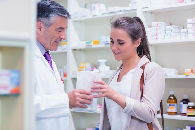 Pharmacist giving paper bag to his customer