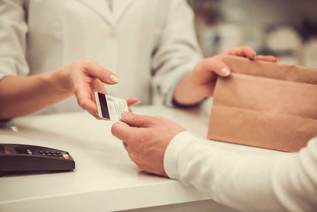 Pharmacist giving a purchase to a client and talking.