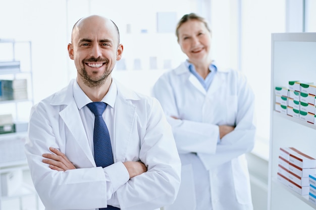 Pharmacist and his assistant standing near the showcase with medicines