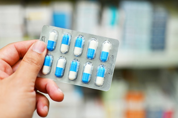 Pharmacist holding blue capsule pack in pharmacy store