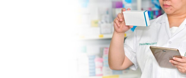 Pharmacist holding medicine box and touch pad for search bar on display in  drugstore