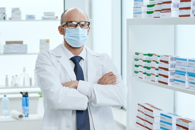 Foto farmacista in una maschera protettiva in piedi nella sua farmacia. foto con copia-spazio.