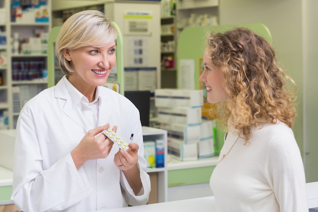 Pharmacist showing blister packs to costumer 