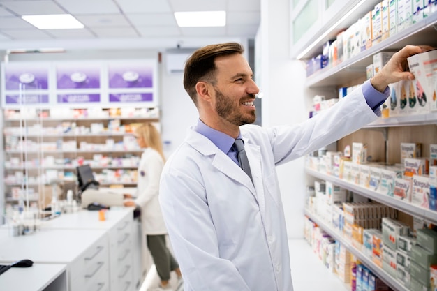 Farmacista che lavora nel negozio di farmacia e che organizza scatole di medicinali sullo scaffale.