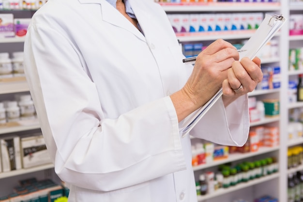 Pharmacist writing prescription on clipboard