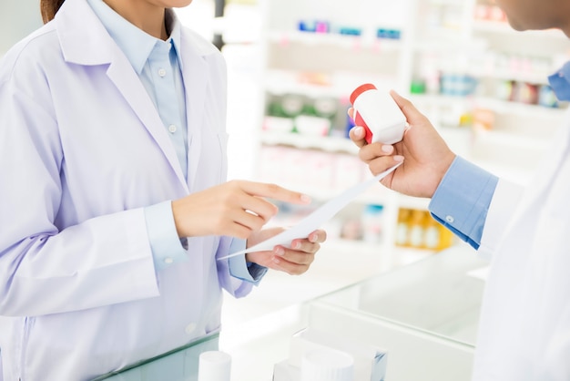 Pharmacists showing medicine bottle and discussing prescription drug in a pharmacy.