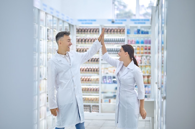 Pharmacists in white robes greeting each other in the workplace