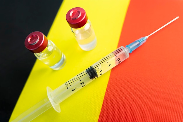 Pharmacology and Medicine Belgium concept vaccine against coronavirus covid national pharmacological industry Vaccine ampoules syringe against the background of national flag