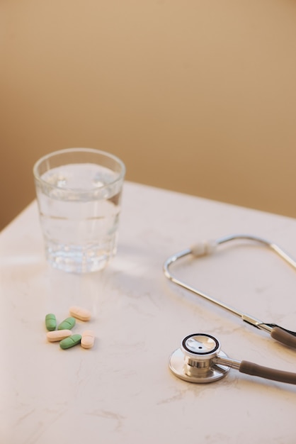 白いテーブルの上の薬局の背景。白い背景の上のタブレット。丸薬。薬と健康。カプセルのクローズアップ。白い木製の背景の聴診器。