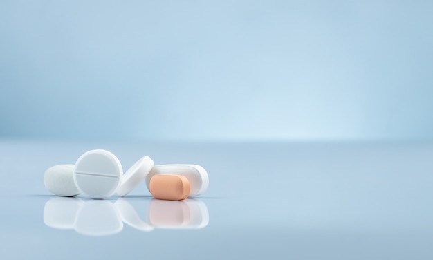 Photo pharmacy drugstore product. pile of orange and white tablets pill on gradient background. different size and shape tablets pills. pharmaceutical industry. medicine in hospital. retail drug market.