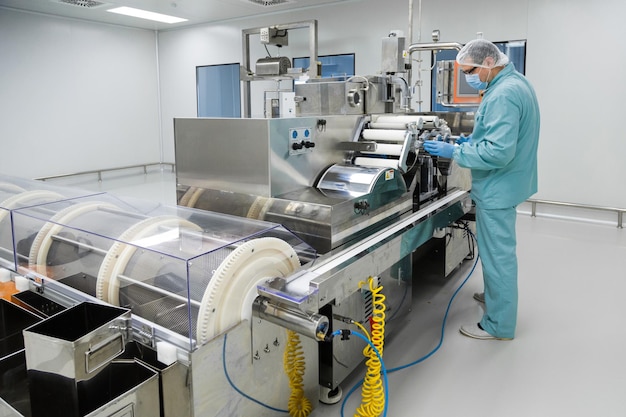 製薬機器で動作する滅菌作業条件で防護服の製薬業界工場の男性労働者