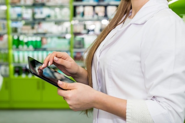 Pharmacy worker checking something in tablet .