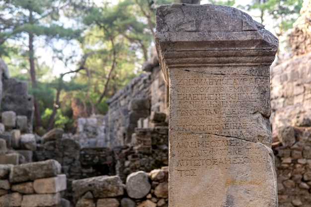 Phaselis, turkey - november 08, 2021: half-erased antique greek inscription on a stone among the ruins of ancient city